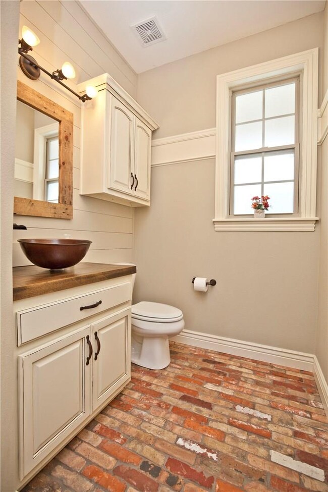 Quaint half bath with brick floor, shiplap wall an