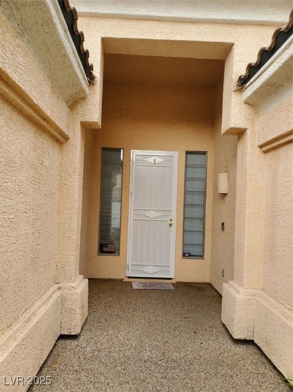 Doorway to property featuring stucco siding