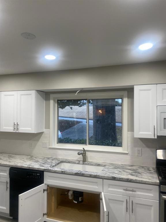 Kitchen with dishwasher, stainless steel stove, white microwave, a sink, and white cabinetry