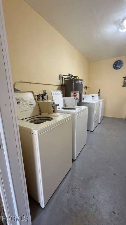 Community laundry room featuring unfinished concrete flooring, independent washer and dryer, and water heater