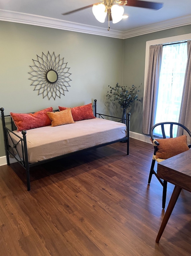 Living area featuring crown molding, dark wood-style floors, and a ceiling fan