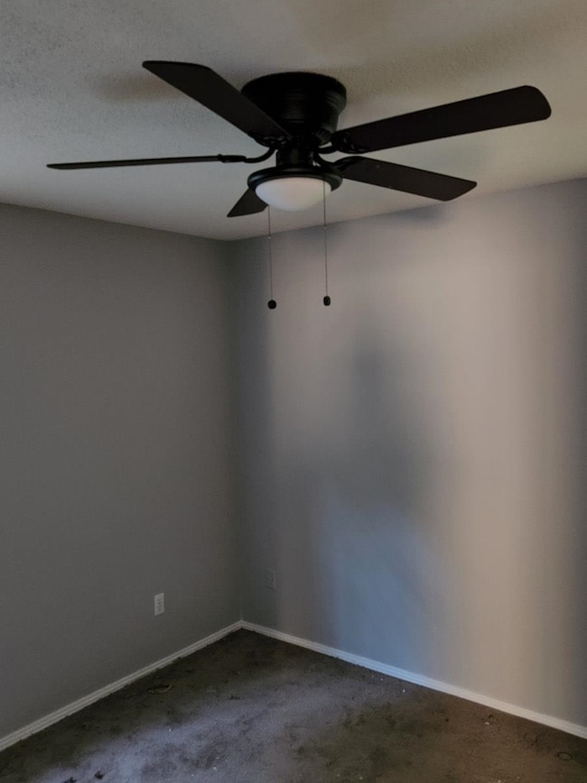 Carpeted spare room featuring a ceiling fan and ba