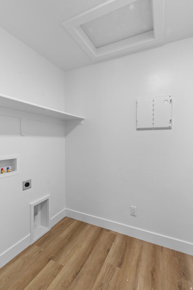 Laundry room with wood finished floors, hookup for a washing machine, electric dryer hookup, and attic access