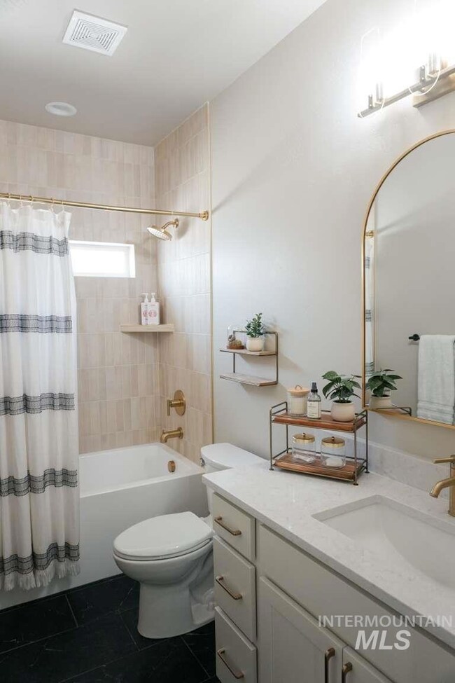 Full bathroom featuring shower / tub combo, vanity, and dark tile patterned flooring