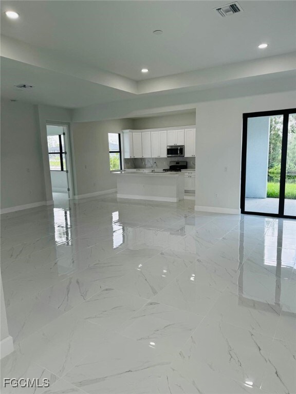 Unfurnished living room featuring light marble finish floors and recessed lighting