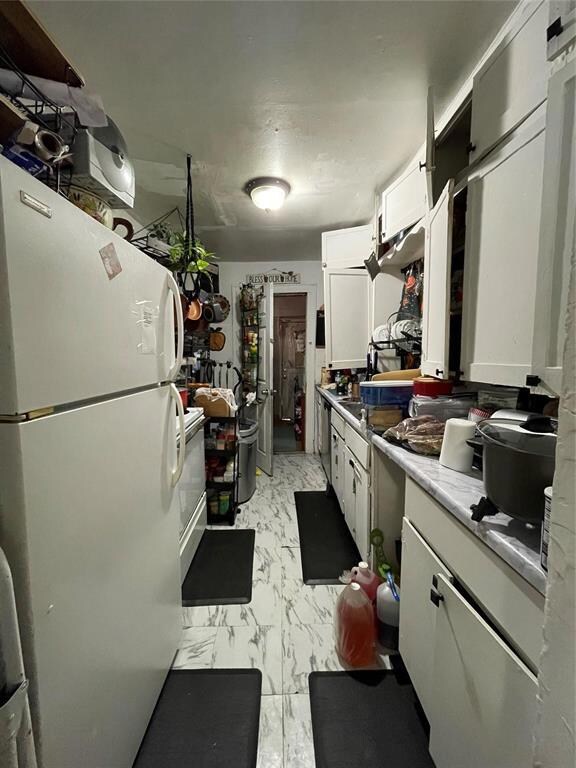 Kitchen featuring white cabinetry and white refrig