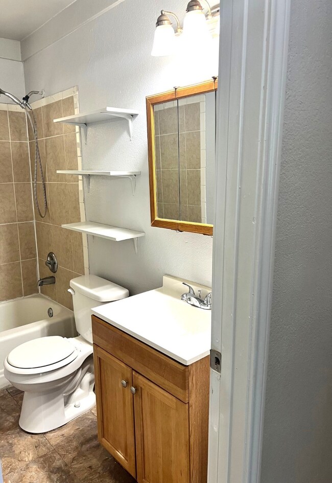 Full bathroom featuring vanity, shower / bath combination, and a textured wall