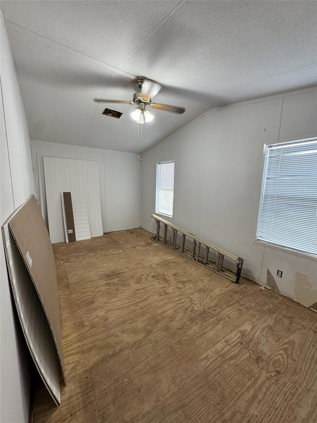 Empty room featuring lofted ceiling, ceiling fan,