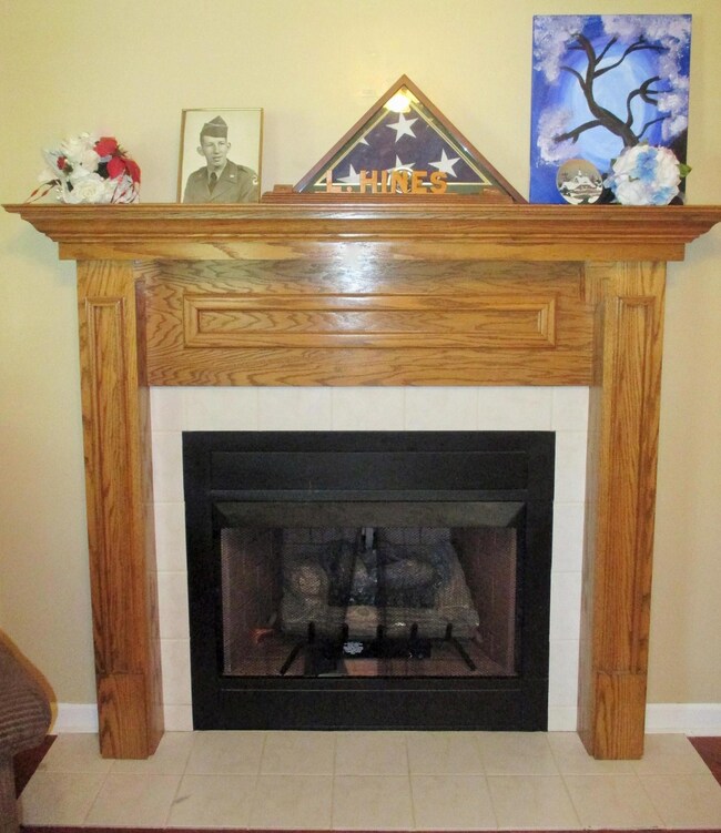 Gas log fireplace has tile hearth & surround with an oak mantle.
