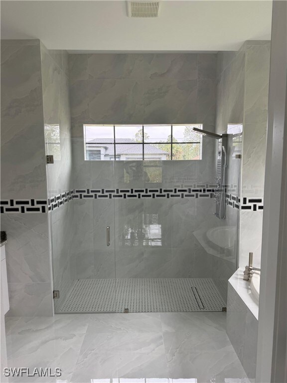 Bathroom featuring a bath, visible vents, marble f