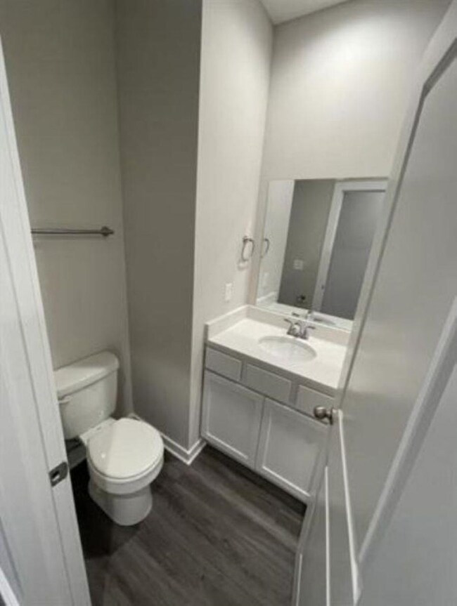 Bathroom featuring vanity, toilet, wood finished floors, and baseboards