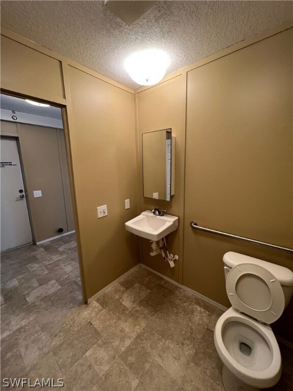 Bathroom with sink, tile flooring, and a textured ceiling