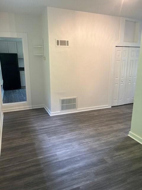 Empty room with dark wood-type flooring, visible v