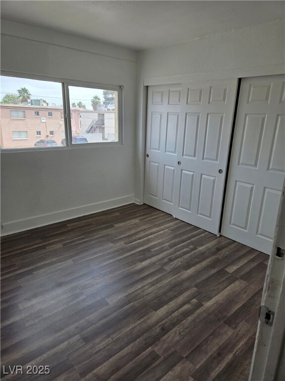 Unfurnished bedroom featuring dark wood-style floo