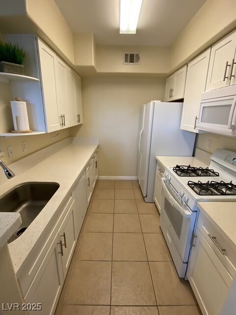 Kitchen featuring range, a sink, white cabinets, a