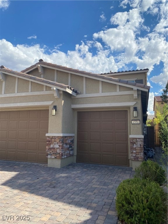 View of front of property with stone siding, stucco siding, decorative driveway, and a tiled roof