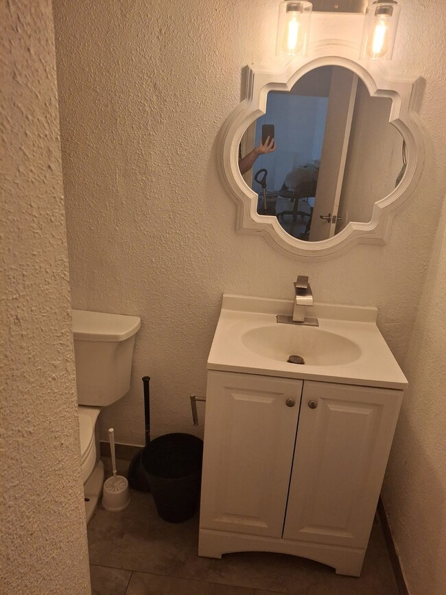 Half bath featuring a textured wall, vanity, and dark tile patterned floors