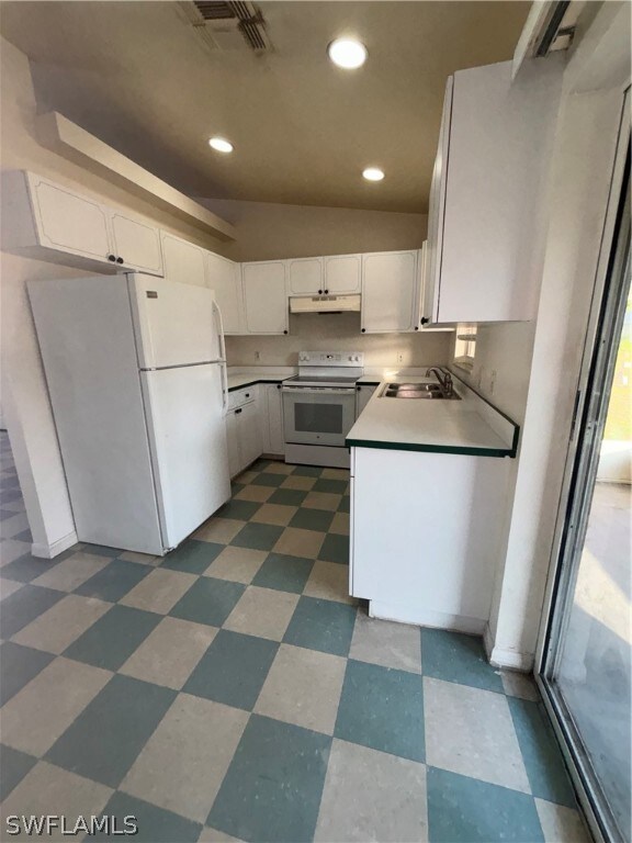 Kitchen with range hood, white cabinets, range with electric cooktop, and refrigerator