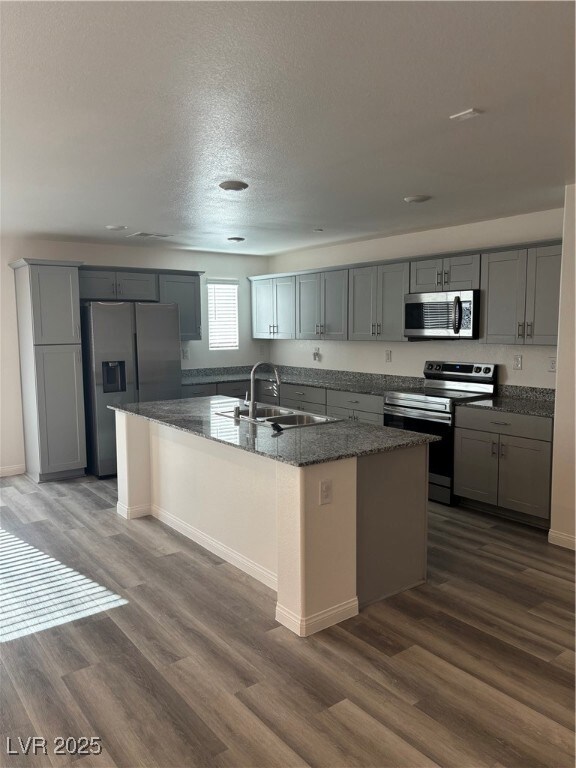 Kitchen with stove, refrigerator, a sink, and gray