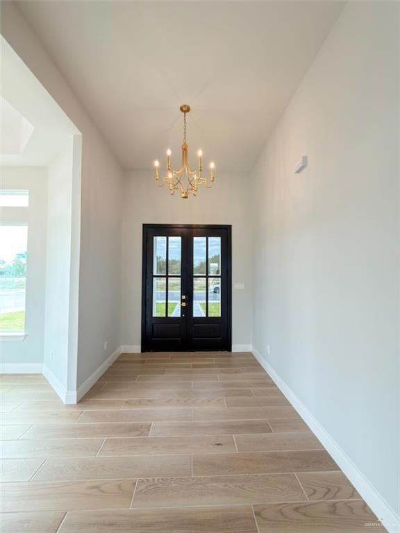 Foyer entrance featuring wood tiled floors, french doors, and a chandelier