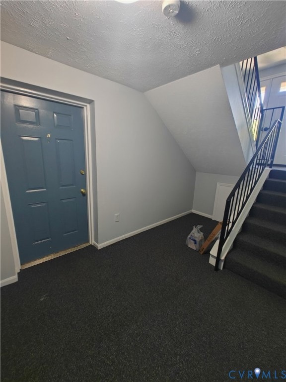 Additional living space with stairway, dark colored carpet, lofted ceiling, and a textured ceiling