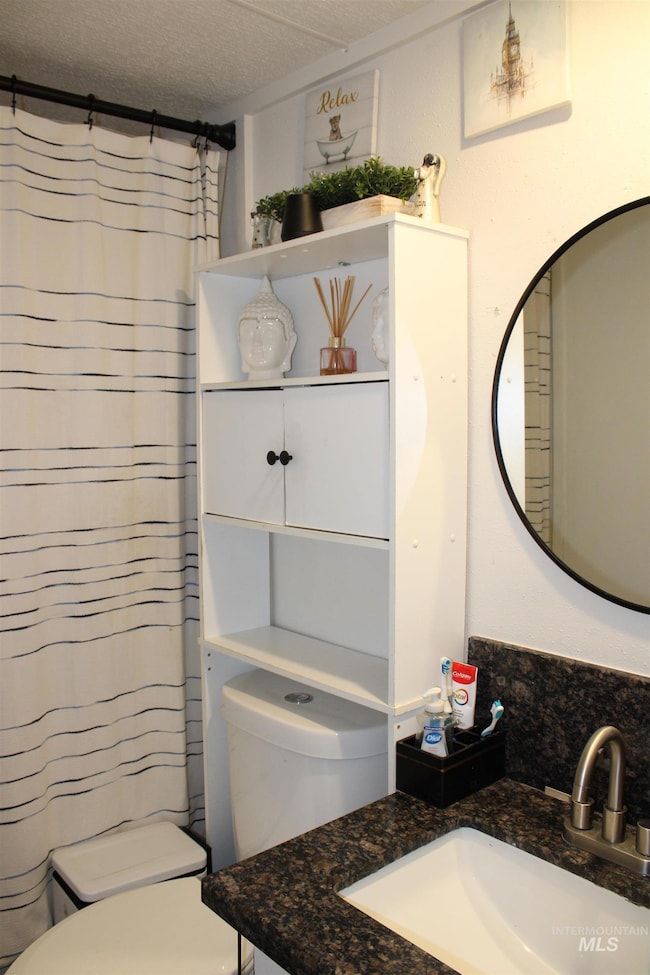 Full bathroom with vanity, a shower with curtain, and a textured ceiling