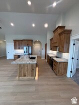 Kitchen featuring arched walkways, a kitchen island with sink, brown cabinetry, black stove, and recessed lighting