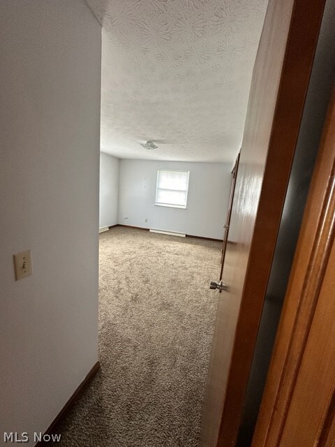 Additional living space with a textured ceiling and dark carpet