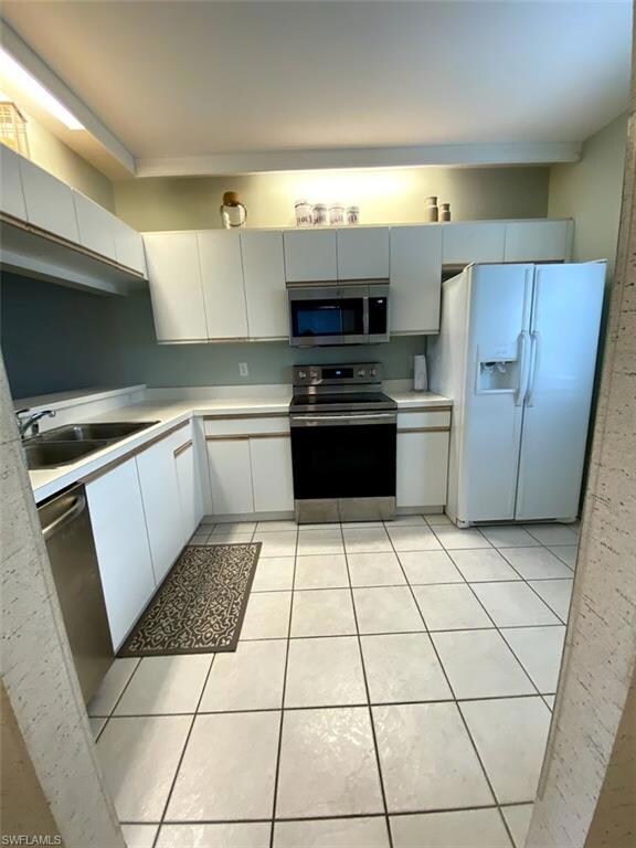 Kitchen with white cabinets, light tile patterned 