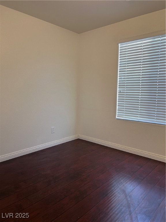 Spare room featuring baseboards and dark wood-styl