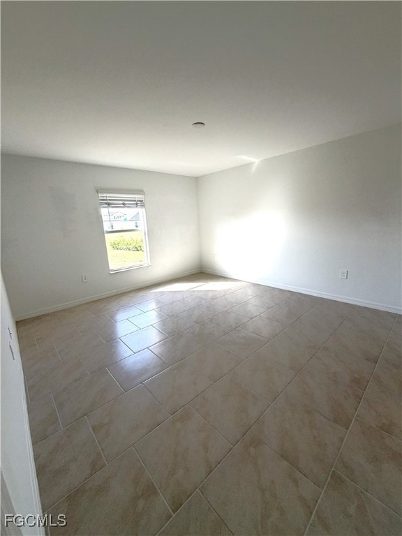 Unfurnished room with light tile patterned flooring and baseboards