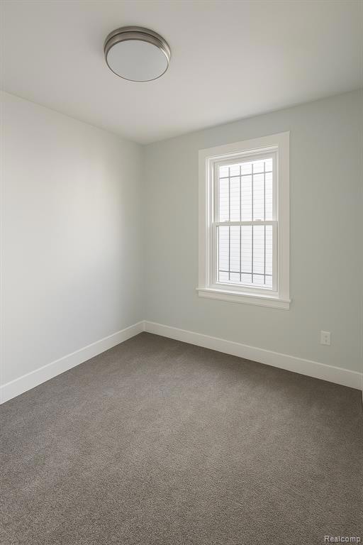 Carpeted spare room featuring baseboards