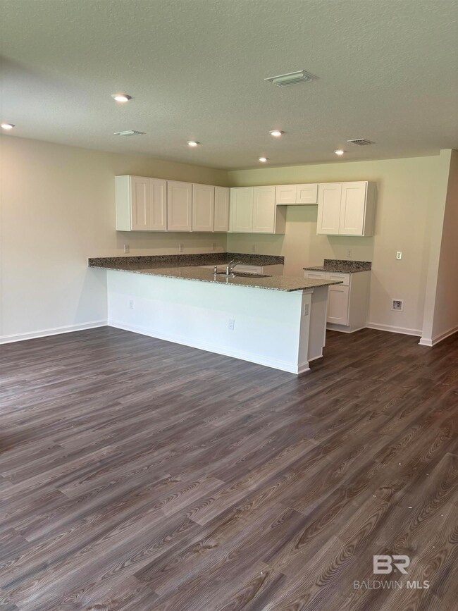 Kitchen featuring white cabinetry, sink, dark stone countertops, dark hardwood / wood-style floors, and a textured ceiling