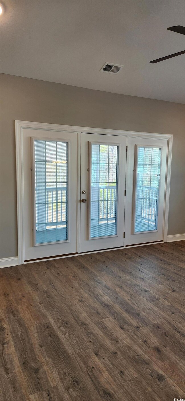 Doorway with ceiling fan and dark hardwood / wood-