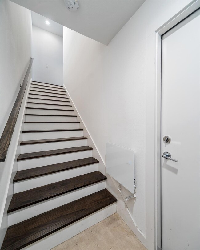 Staircase featuring concrete flooring and recessed