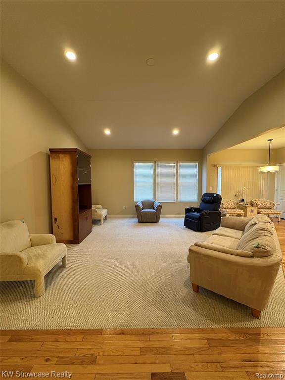 Living area with lofted ceiling, recessed lighting, light wood-type flooring, and light colored carpet