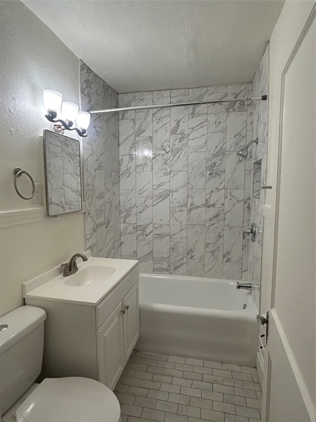Bathroom featuring bathtub / shower combination, vanity, a textured ceiling, and light tile patterned floors