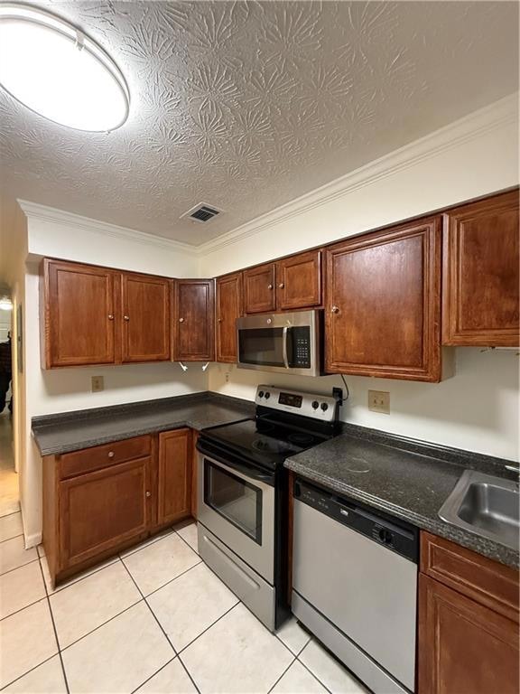 Kitchen with stainless steel microwave, dishwasher, stove, dark countertops, and ornamental molding