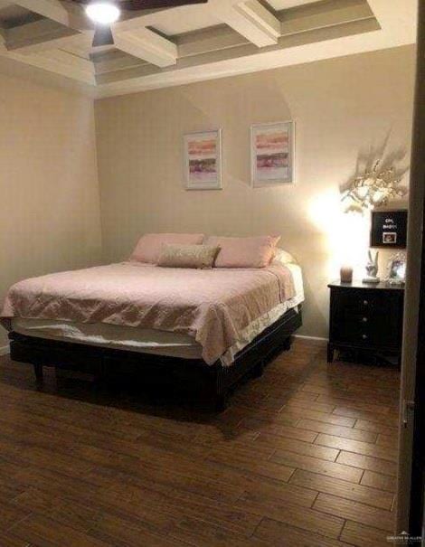 Bedroom with coffered ceiling, beamed ceiling, wood finished floors, and ceiling fan