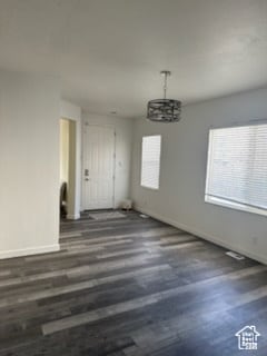 Unfurnished dining area with plenty of natural light, dark wood-type flooring, and a chandelier