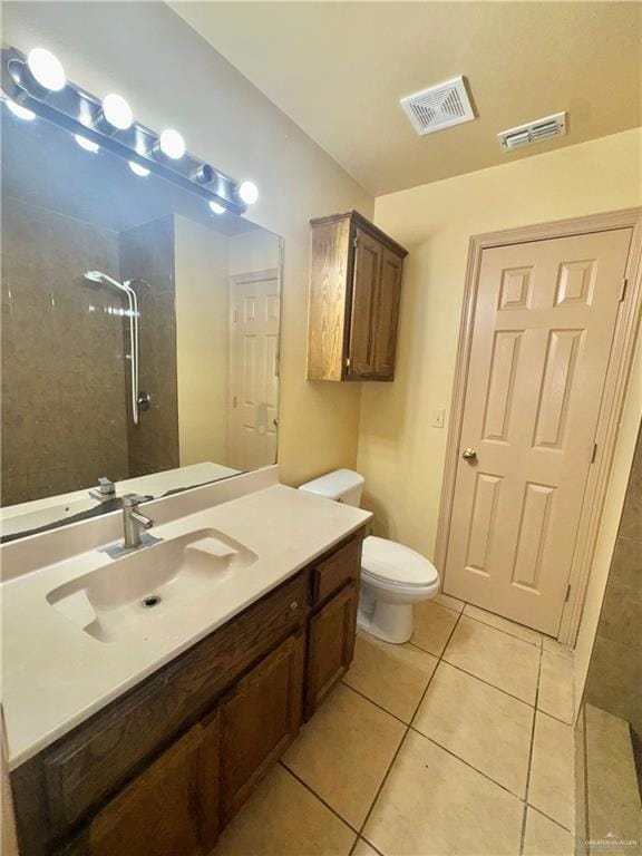 Bathroom with a tile shower, vanity, and tile patterned flooring