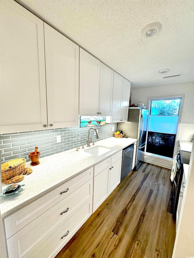 Kitchen featuring white cabinetry, sink, stainless