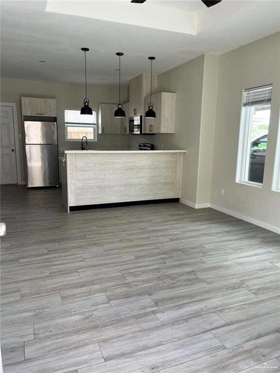 Kitchen featuring stainless steel appliances, modern cabinets, baseboards, and light countertops