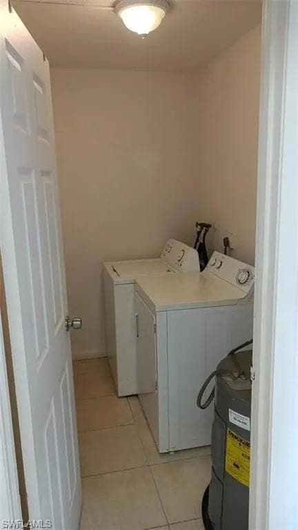 Washroom with washer and dryer, light tile patterned floors, and water heater