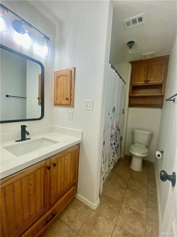 Full bathroom featuring tile patterned flooring, visible vents, baseboards, toilet, and vanity