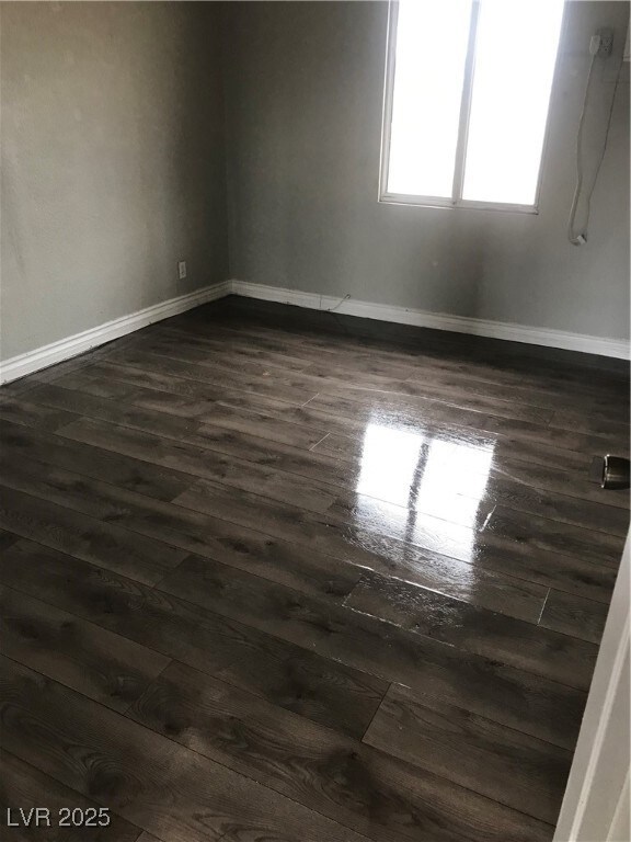 Unfurnished room with dark wood-type flooring and baseboards