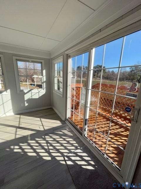 Unfurnished sunroom with wood finished floors and crown molding