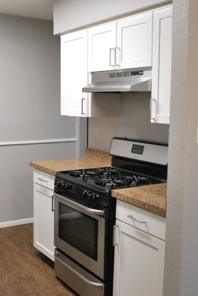 Kitchen featuring gas stove, white cabinetry, and under cabinet range hood