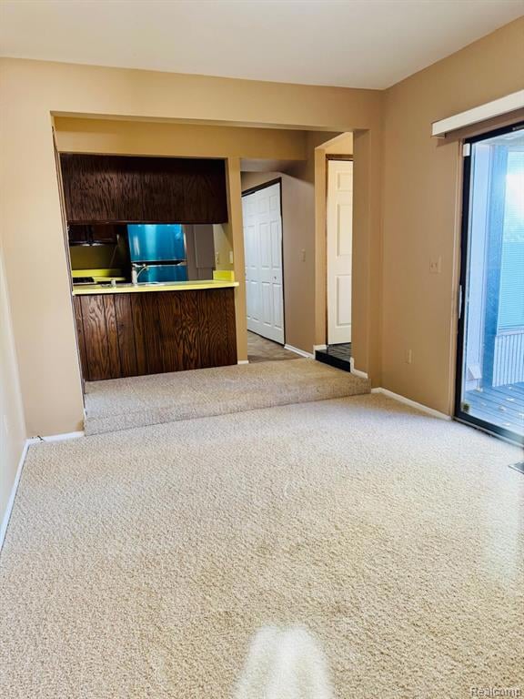Unfurnished living room featuring light colored carpet and baseboards