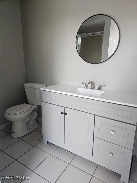 Bathroom with vanity, tile patterned floors, toilet, and baseboards